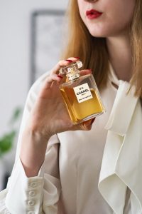 Close-up d'une femme tenant un flacon de parfum Chanel N°5, mettant en valeur l'élégance à Paris.