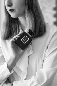 Stylish woman showcasing a luxury perfume bottle in classic monochrome. Femme élégante présentant un flacon de parfum de luxe en monochrome classique.