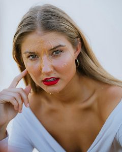 Striking portrait d'une femme avec du miel sur le visage et les cheveux mouillés, montrant une expression intense