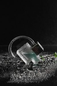 Stylish flacon de parfum en verre avec des gouttes d'eau, exhalant une sensation de fraîcheur sur un fond sombre