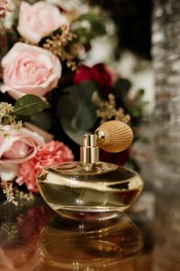 Gros plan d'un flacon de parfum vintage avec des roses roses, évoquant l'élégance et le luxe.