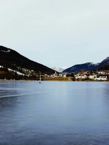 Serene vue hivernale de San Valentino Alla Muta avec lac gelé et maisons de village.