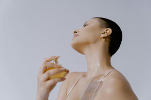 A woman with short hair applies fragrance to her neck, exuding elegance and style. Une femme aux cheveux courts applique du parfum sur son cou, dégageant élégance et style.