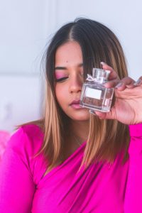 Portrait d'une femme tenant un parfum, mettant en avant la beauté et l'élégance.