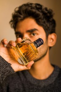 Asian man holding a perfume bottle in a close-up shot. Perfect for fashion and beauty themes. Homme asiatique tenant un flacon de parfum en gros plan. Parfait pour les thèmes de la mode et de la beauté.