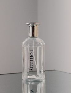 Flacon de parfum minimaliste dans une prise de vue en studio avec surface réfléchissante et tons neutres.