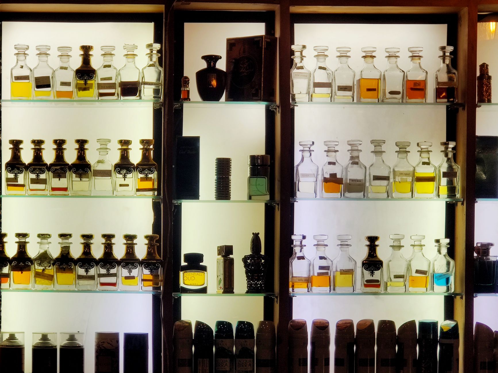Flacons de parfum présentés sur une étagère lumineuse