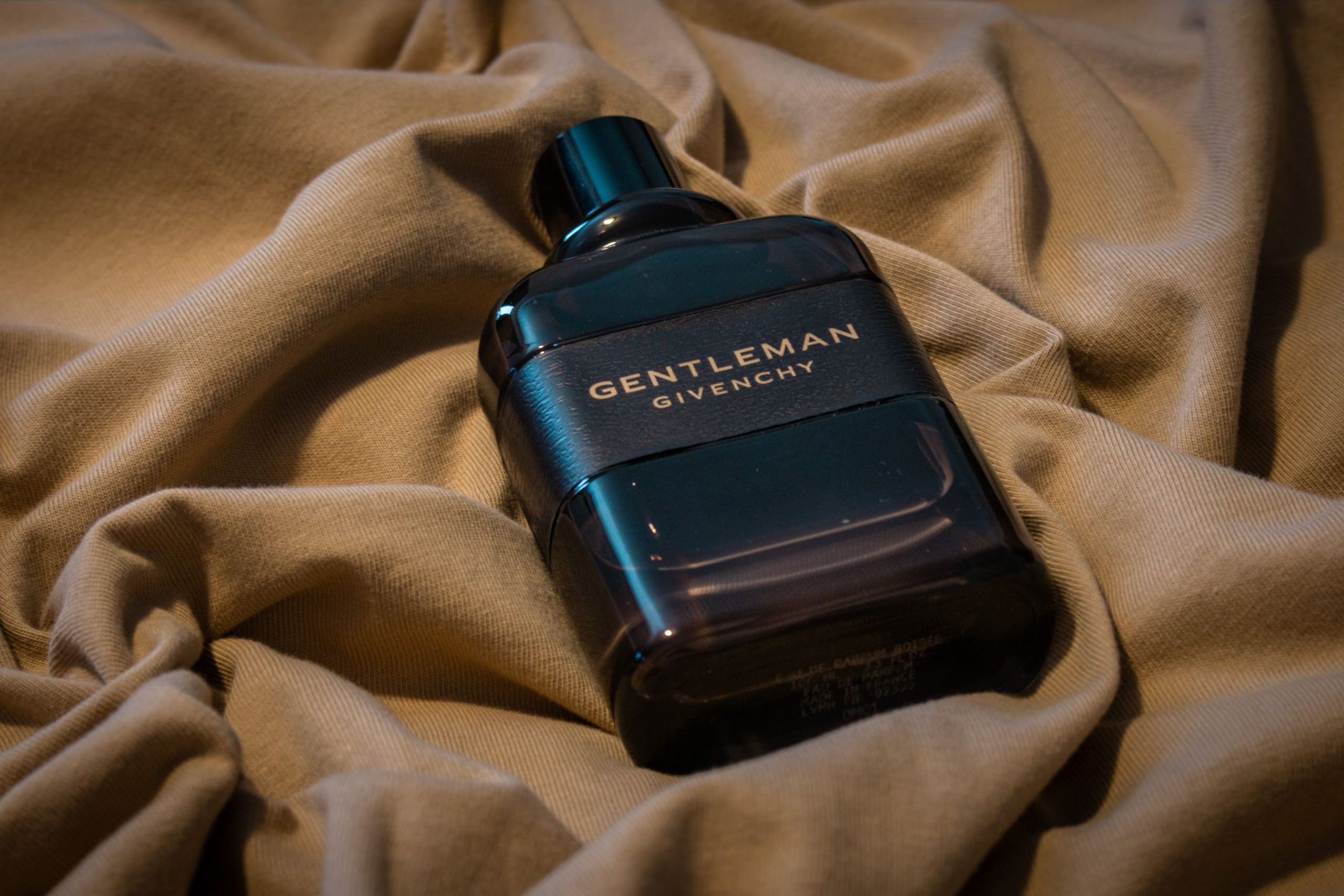 Flacon de parfum boisé posé sur un tissu sombre