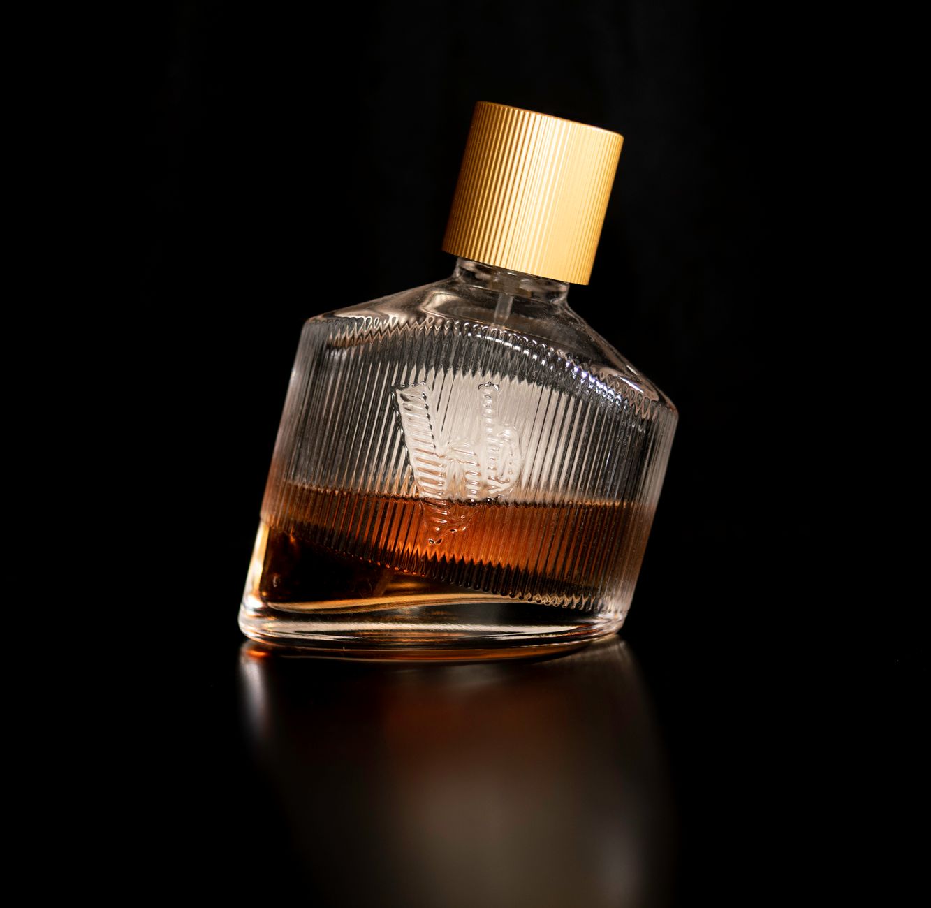 Flacon de parfum à capuchon doré sur fond noir brillant