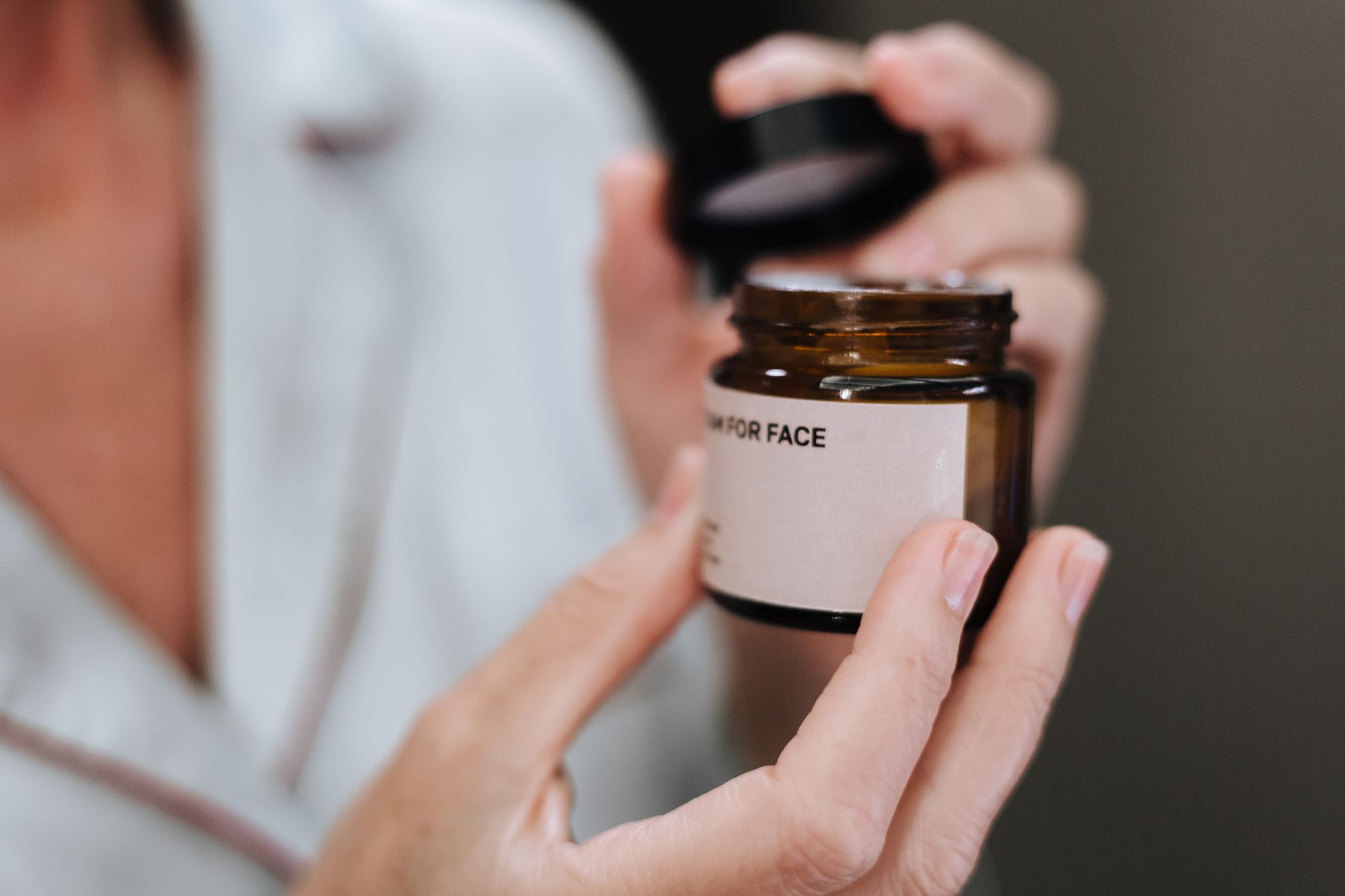 Pot de crème visage ouvert entre les mains