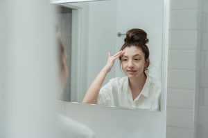 Femme appliquant une crème sur le visage devant le miroir