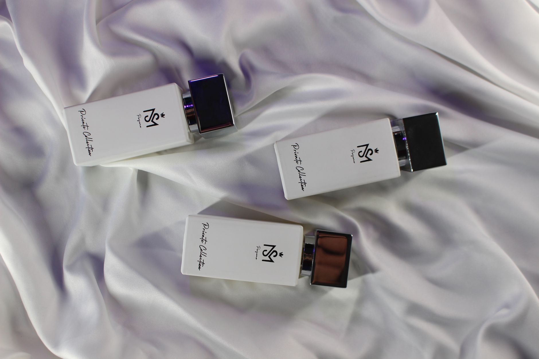 Trois flacons de parfum sur un tissu de soie blanc